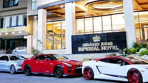 Hotel Grand Xing Imperial con dos coches deportivos de lujo estacionados frente a él.