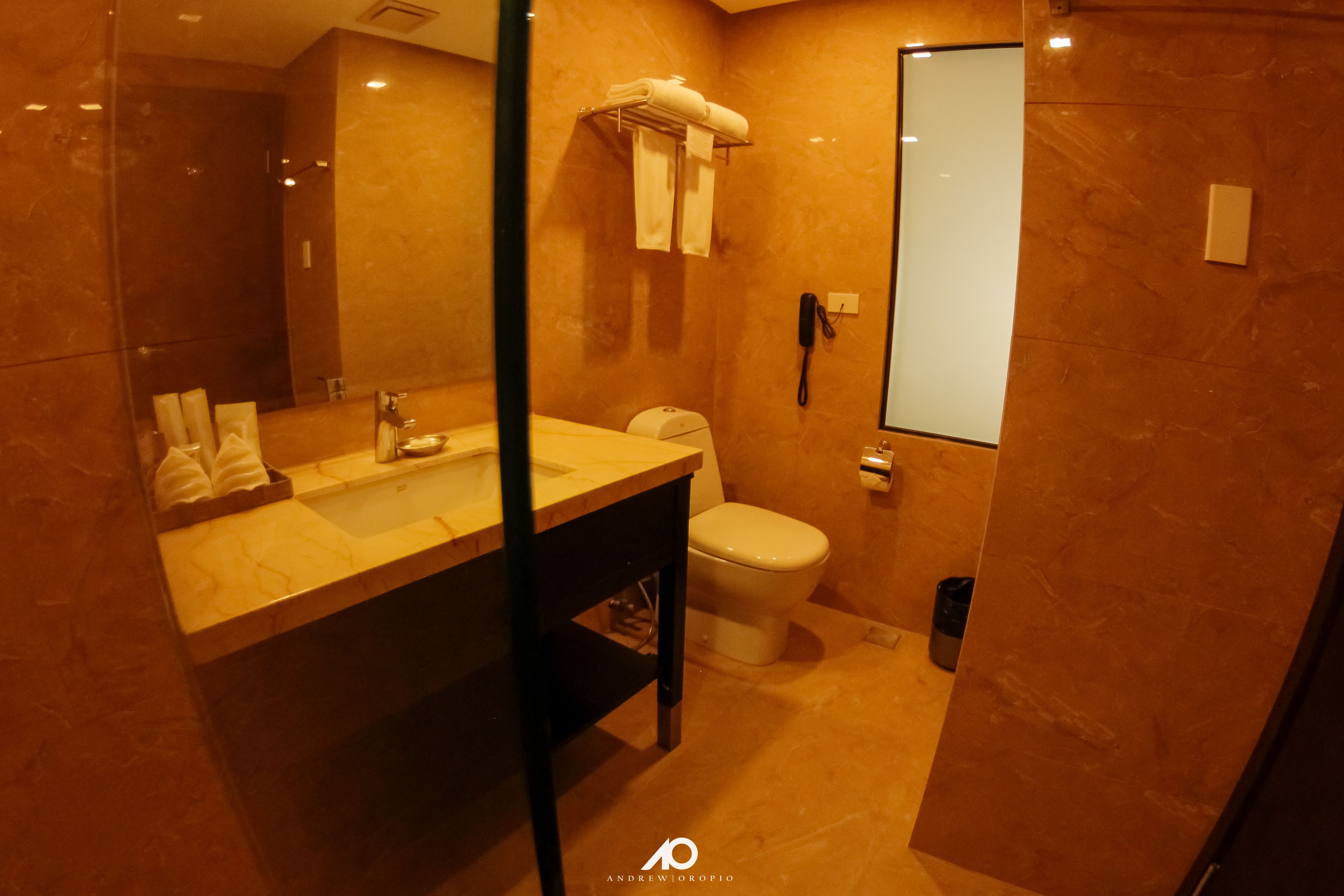 A modern bathroom with a marble sink, a toilet, and a glass shower enclosure.