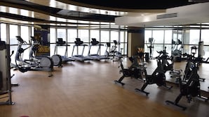 Un gimnasio amplio con numerosas caminadoras, bicicletas estáticas y otros equipos de cardio.