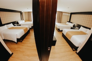 A hotel room with two beds, a wooden floor, and a large mirror.