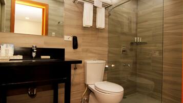 Un baño moderno con lavamanos, inodoro y ducha con mampara de vidrio.