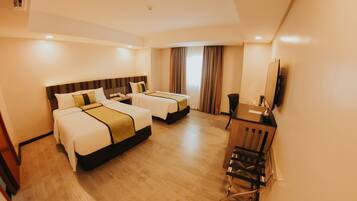 A hotel room with two beds, a desk, a chair, and a television.