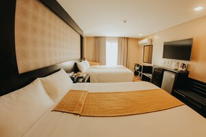 Una habitación de hotel con dos camas, un escritorio, televisor y minibar.