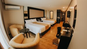 Habitación de hotel con dos camas, un escritorio, una silla y un televisor.