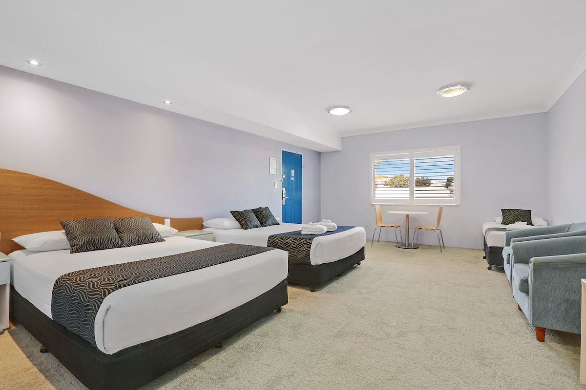 Una habitación de hotel con dos camas, una mesita y una silla.