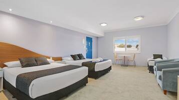 A hotel room with two beds, a small table, and a chair.