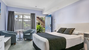 Une chambre d’hôtel avec un lit, une chaise, un bureau et une vue sur l’extérieur.