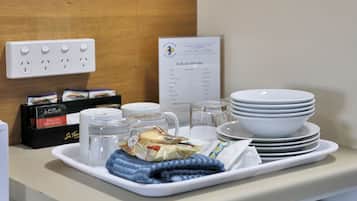 Minibar de hotel con una bandeja que contiene una toalla, recipientes de vidrio y aperitivos envasados.