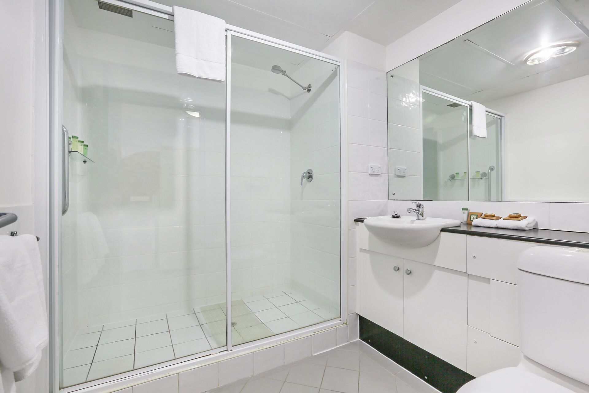 Un baño moderno con ducha acristalada, lavamanos y espejo.