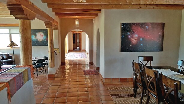Un ampio corridoio con pavimento piastrellato, travi in legno e un grande quadro a tema galassia sulla parete.