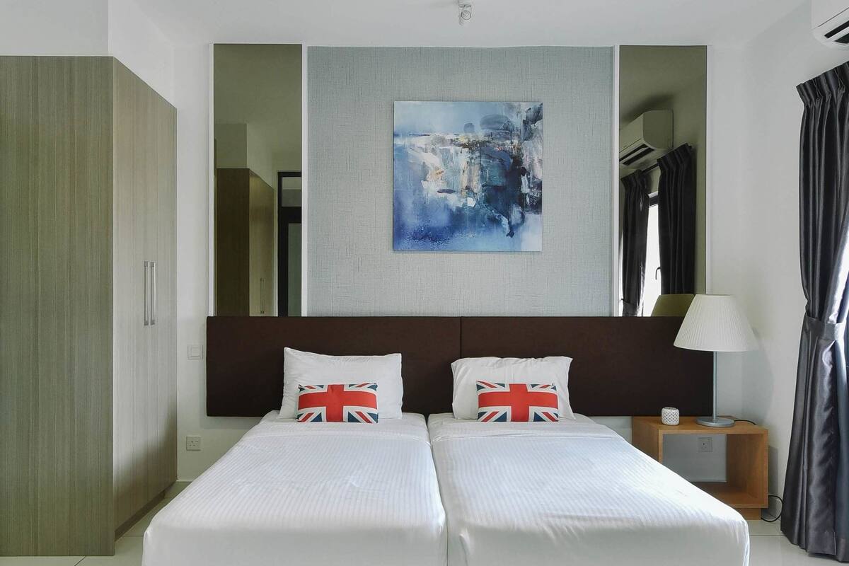 A hotel room with two beds, a large painting on the wall, and a view of the city through the window.