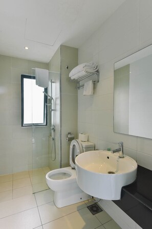 A modern bathroom with a glass-enclosed shower, a white toilet, and a sink with a mirror above it. - 1 Tebrau Suites by Subhome (Johor Bahru)