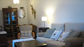 A living room with a sofa, armchair, and a small table. There is a lamp, a mirror, and a cabinet in the room. - MORISCA DE LA LUNA HOUSE IN GRANADA. PATIO AND GARDEN. (Granada)