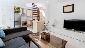 A modern apartment with a living room, kitchen, and dining area. It features a large TV, a sofa, and a dining table. - Alfarería Terrace. 2 bedrooms, private terrace (Sevilla)
