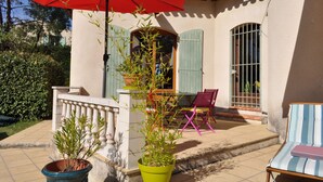 A patio with a red umbrella, a table, and two chairs. - Family home, swimming pool, 5 bedrooms with private bathrooms Enclosed garden (Saint-Geniès-De-Malgoirès)