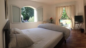 A bedroom with a bed, a TV, and a view of a pool and garden. - Family home, swimming pool, 5 bedrooms with private bathrooms Enclosed garden (Saint-Geniès-De-Malgoirès)