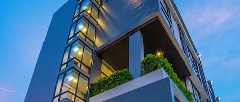 Un bâtiment moderne avec une façade en verre, une enseigne de restaurant bien visible et un potelet d’hydrant situé devant.