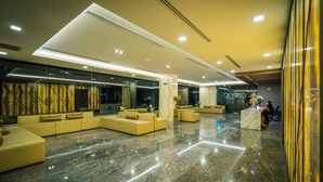 Eine geräumige Lobby mit Marmorboden, modernen Sofas und einem Empfangstresen.