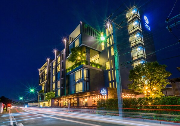 A modern building with multiple floors, large windows, and outdoor seating areas.