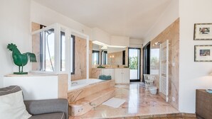 Une salle de bain moderne avec un sol en marbre, une baignoire et un coq décoratif vert.