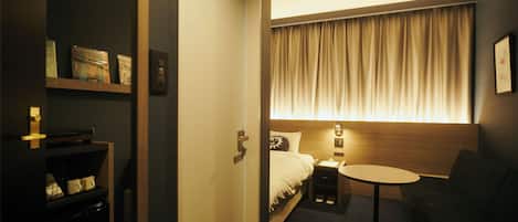 A hotel room with a bed, bedside table, and a small round table.