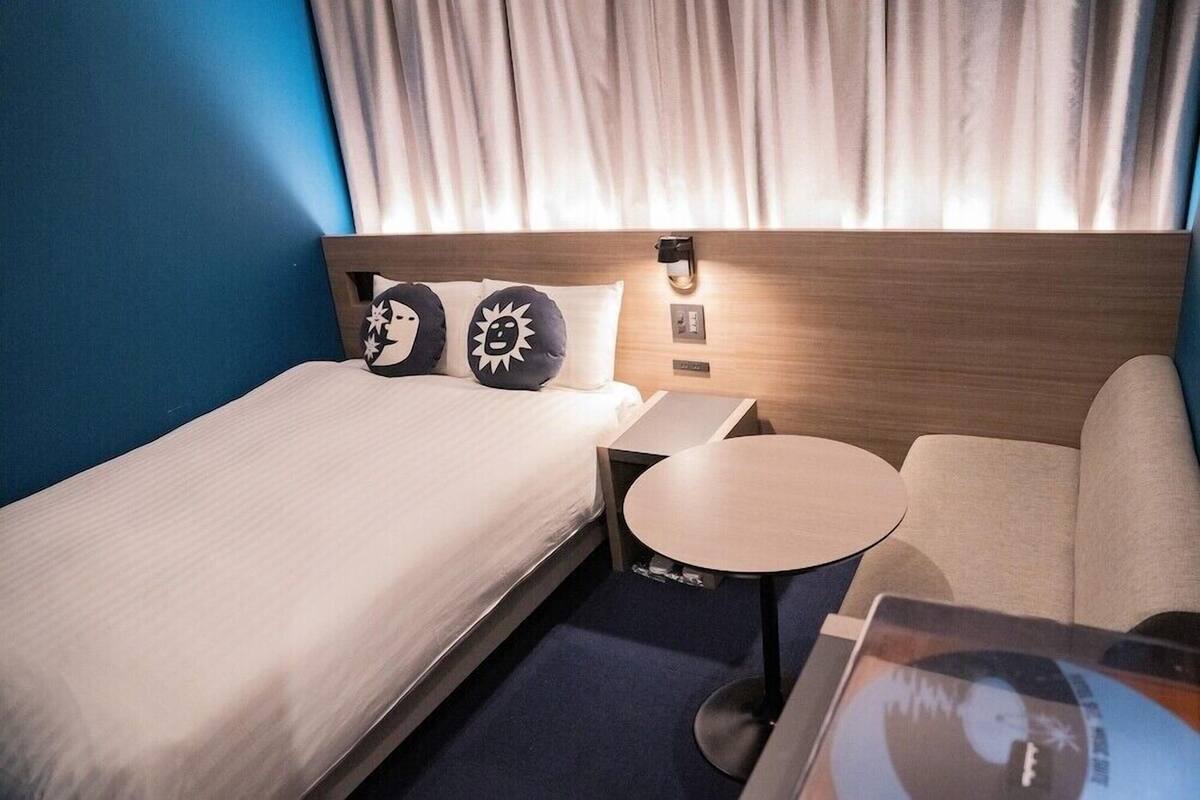 A hotel room with a bed, a small table, and a sofa.
