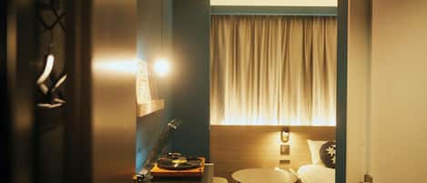 A hotel room with a bed, a small table, a lamp, and a record player.