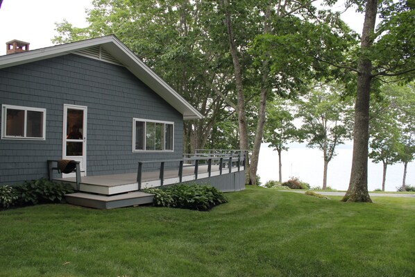 A house with a grey exterior, a porch, and a view of a lake.