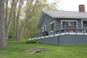 A house with a grey exterior, a balcony, and a stone foundation.