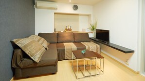 A modern living room with a sectional sofa, a coffee table, a flat-screen TV, and a window with blinds. - Kyo Koyado Benten (Kyoto)
