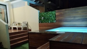 A hot tub area with wooden steps leading up to it, a small seating area with chairs, and a green hedge in the background. - Parque Tecnológico Villa, ideal for couples and families. Swimming pool, games, park, etc. (Málaga)