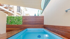 A rectangular swimming pool with a wooden deck, surrounded by a wooden wall and a green hedge. - Parque Tecnológico Villa, ideal for couples and families. Swimming pool, games, park, etc. (Málaga)