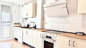 A modern kitchen with white cabinets, a built-in oven, and a large window. - Parque Tecnológico Villa, ideal for couples and families. Swimming pool, games, park, etc. (Málaga)