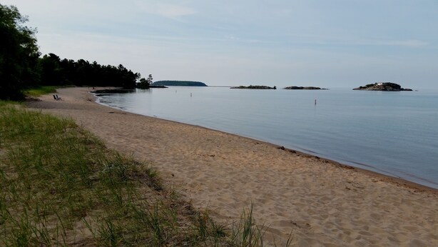 A beach with a sandy shore, calm water, and distant islands. - Charming East side-Marquette Home Convenient to Beach, Nmu & Hospital (Marquette)