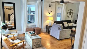 A cozy living room with a sofa, armchair, and coffee table, a fireplace, and a large mirror. - Charming East side-Marquette Home Convenient to Beach, Nmu & Hospital (Marquette)