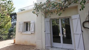 Un edificio con un balcone, una porta con pannelli di vetro e una finestra con persiane.