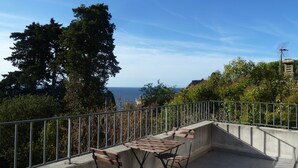 Un balcone con vista sul mare, una ringhiera in metallo e un muro in cemento.