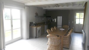 A spacious kitchen with a dining area, large windows, and a washing machine.