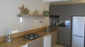 A compact kitchen with a built-in dishwasher, a stove, and a refrigerator.