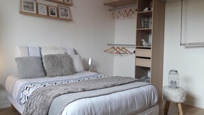 Een slaapkamer met een bed, een kledingkast en een klein krukje.