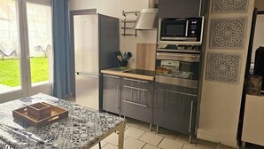 Een kleine keuken met een koelkast, magnetron, oven en een tafel met dienblad.