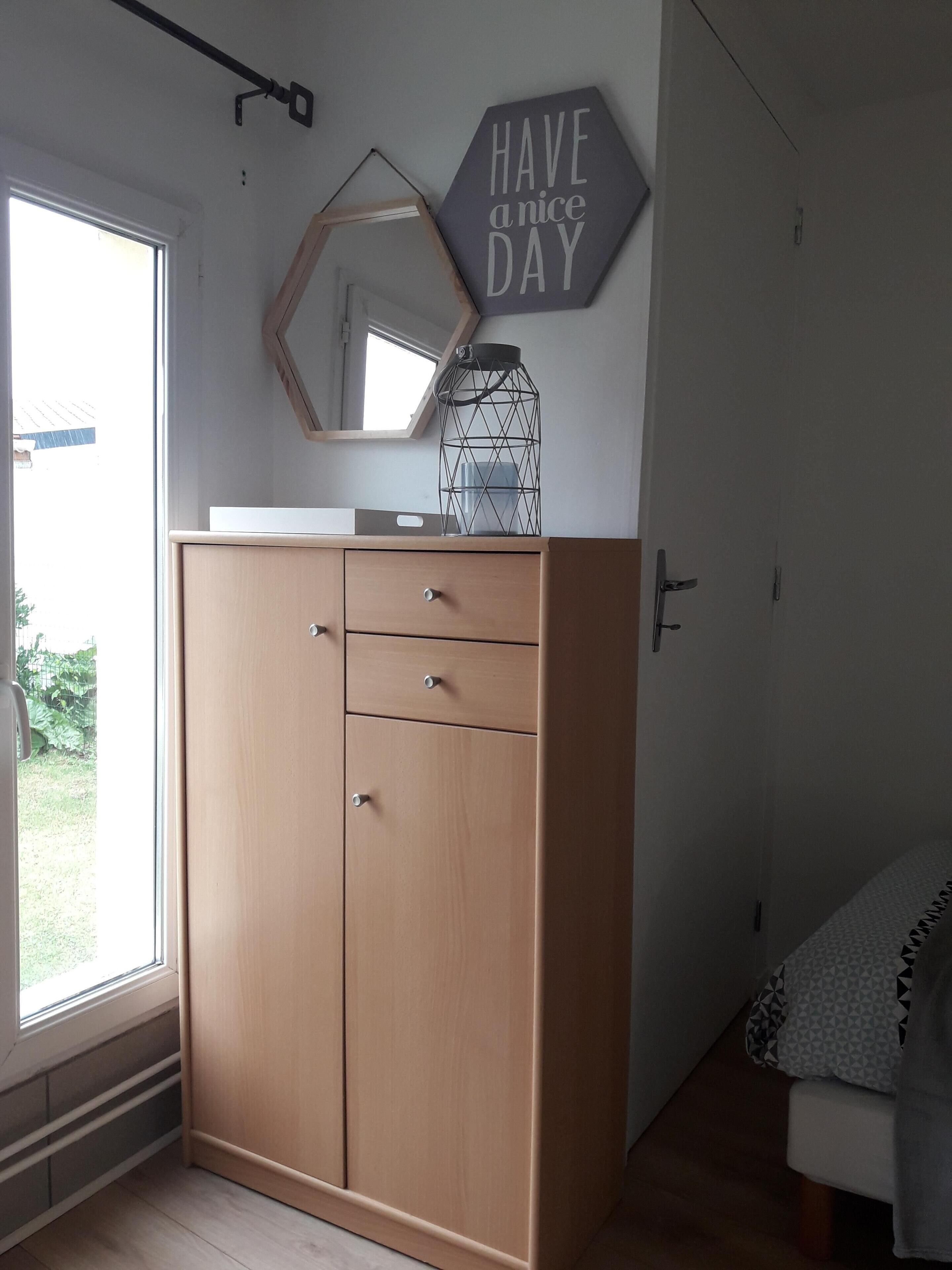 Une pièce avec une armoire en bois, un grand miroir et une pancarte où est écrit « PASSEZ UNE BONNE JOURNÉE ».