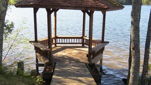 Un kiosque en bois surmonté d’une girouette, situé au bord d’un lac.