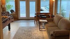L’intérieur d’un chalet en bois chaleureux et accueillant, avec un canapé, une table et un baby-foot.