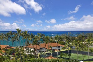 A coastal property with multiple buildings, a tennis court, and a view of the ocean.