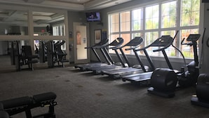 A gym with treadmills, weight machines, and a TV screen. - Welcome To Our Beautiful Villa In The Gorgeous Community Solterra! (Davenport)