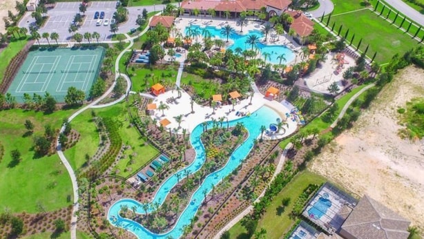An aerial view of a resort with a winding pool, tennis courts, and a large building with a red roof. - Welcome To Our Beautiful Villa In The Gorgeous Community Solterra! (Davenport)