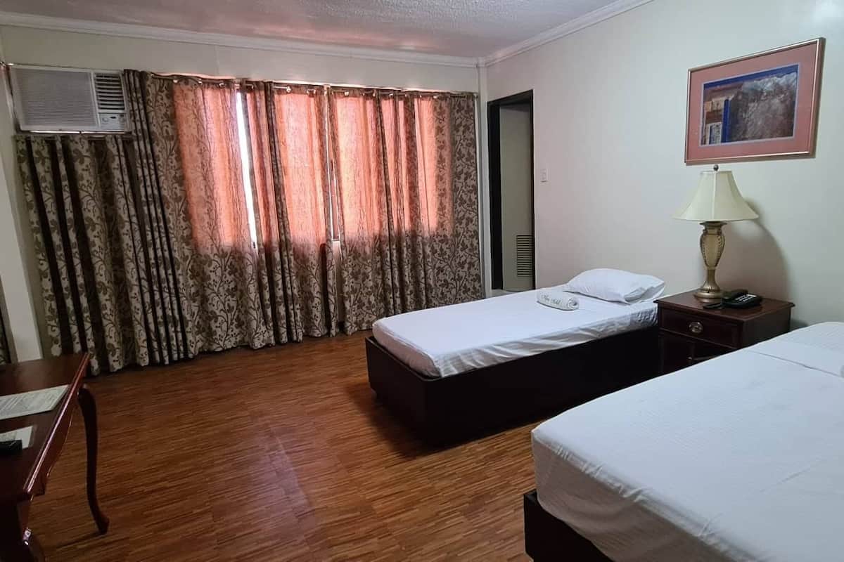 Een hotelkamer met twee bedden, een bureau, een lamp en een schilderij aan de muur.