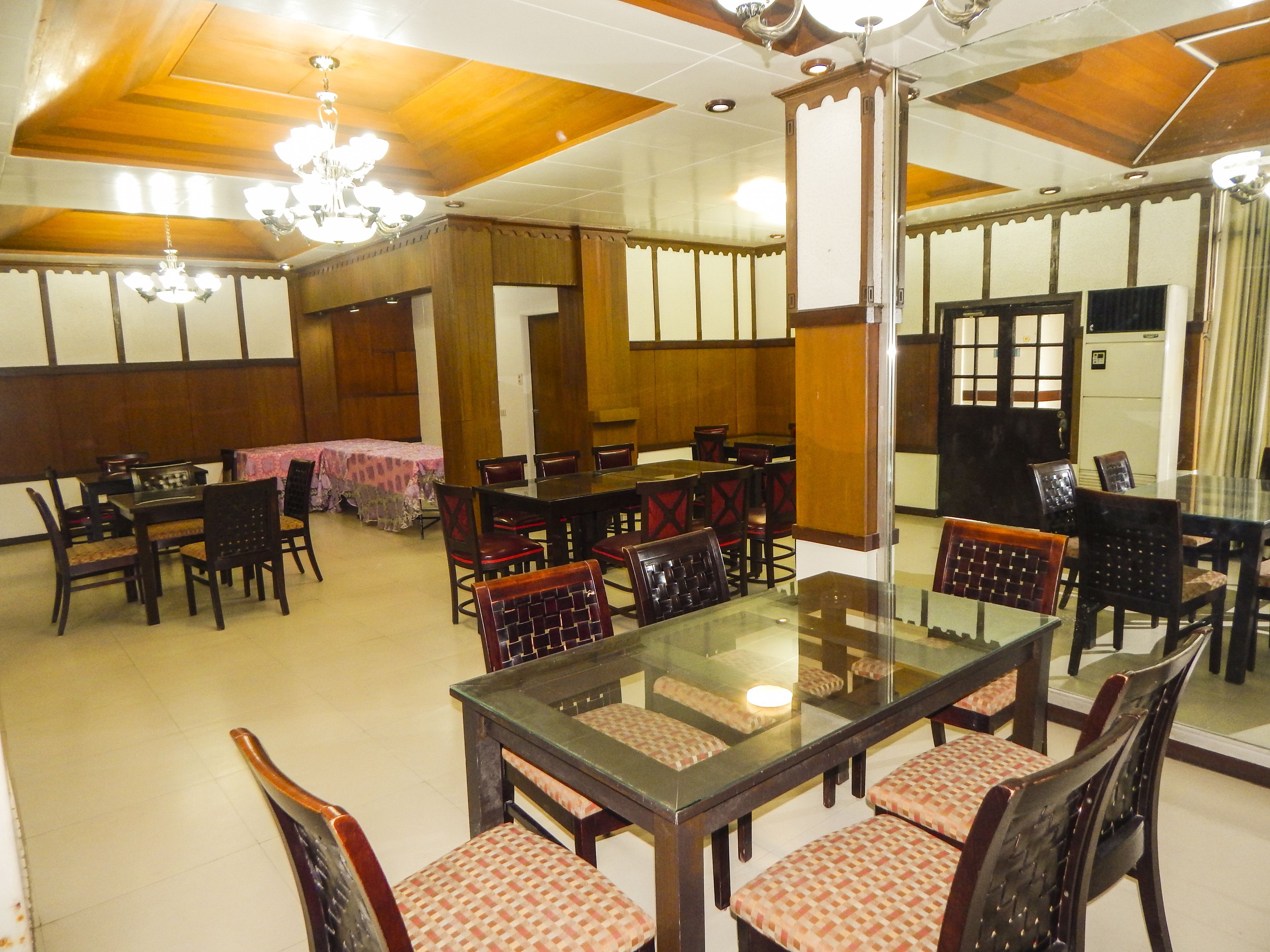 A traditional Japanese-style dining room with wooden paneling, a large central table, and multiple chairs.