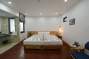 A modern bedroom with a wooden bed, a glass shower enclosure, and a small table with a chair. - Blue Hanoi Inn City Hotel (Hanoi)